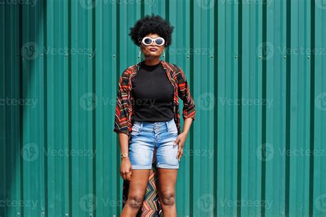 mulher africana com cabelo afro, em shorts jeans e óculos de sol