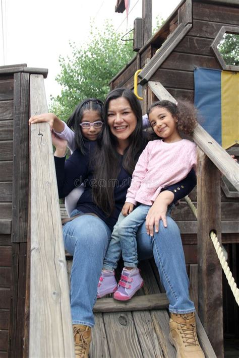 Mother With Two Brunette Latina Daughters Play On Playground Equipment And Spend Time Together