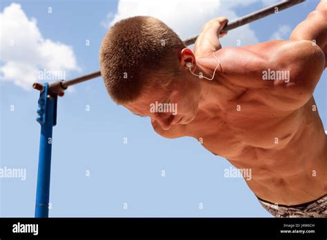Young Strong Athlete Make Exercise On Horizontal Bar Against Blue Sky