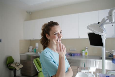 Smiling female dentist in uniform standing with dental tweezersFree