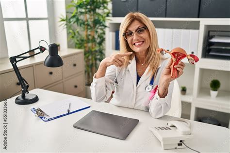 Middle Age Blonde Gynecologist Woman Holding Anatomical Model Of Female Genital Organ Pointing