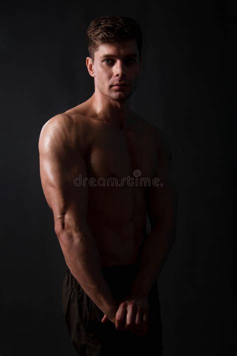 Muscular Bodybuilder Posing With A Naked Torso Against A Black Background Stock Photo Image