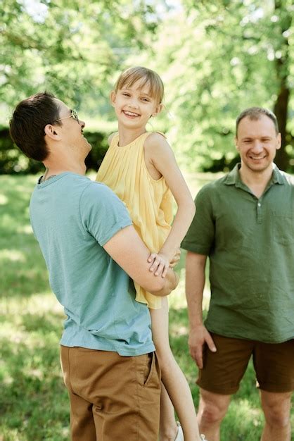 Dos padres de familia gay jugando con niña en el parque al aire libre Foto Premium