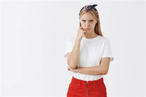 Sérieuse Jeune Fille Blonde Concernée Posant Contre Le Mur Blanc Photo Gratuite