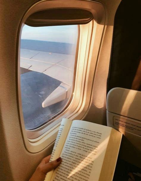 A Person Is Reading A Book While Looking Out An Airplane Window