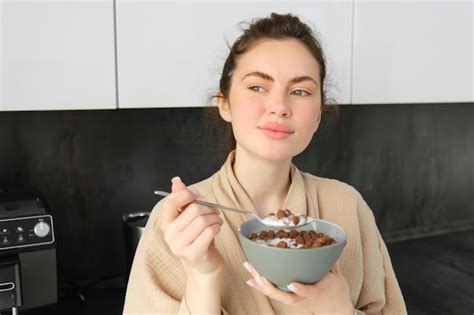 Free Photo Goodlooking Brunette Woman Eating Her Breakfast Standing In Kitchen Near Worktop