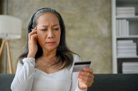 Unhappy Asian Mature Woman Having Financial Problems Or Problems With Her Credit Card Stock