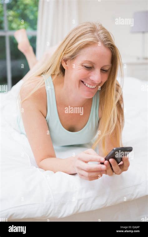 Happy Blonde Using Smartphone On Bed Stock Photo Alamy