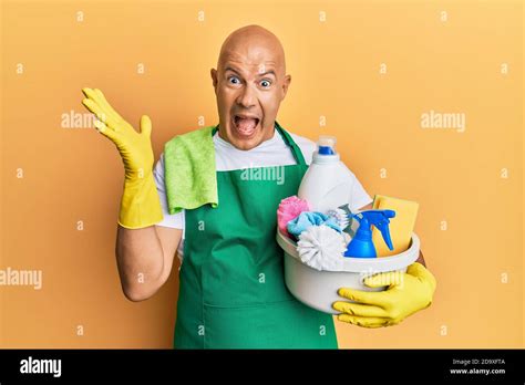 Middle Age Bald Man Wearing Cleaner Apron Holding Cleaning Products