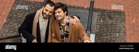 Happy And Stylish Bearded Man Embracing Gay Partner On Escalator Outdoors Banner Stock Image