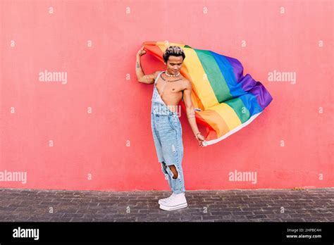Gay Male Holding A Rainbow Lgbt Flag In City Against Pink Wall Stock Photo Alamy