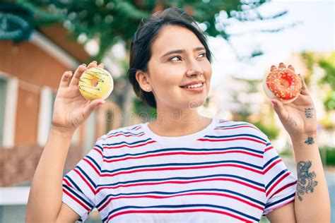 Joven Latina Sonriendo Feliz Sosteniendo Donuts Caminando En La Ciudad Foto De Archivo Imagen
