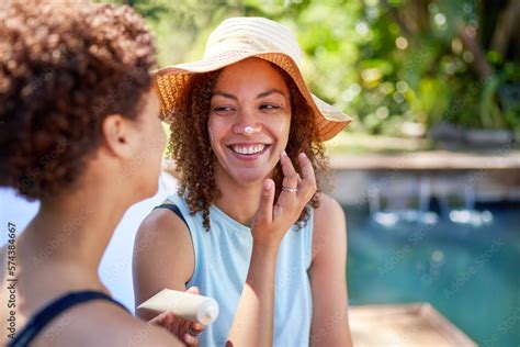 Happy Playful Lesbian Couple Applying Sunscreen To Nose At Poolside Stock Photo Adobe Stock