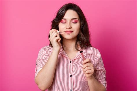 Close Up Portrait Of Beautiful Brunette Woman Holding And Smelling Sweet Lips Gloss Posing With