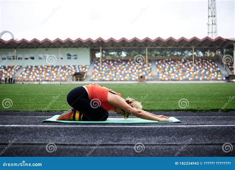 Jeune Femme Décent Blonde En Utilisant Les Les guêtres Supérieures Orange Et Noir Assis Avec Les