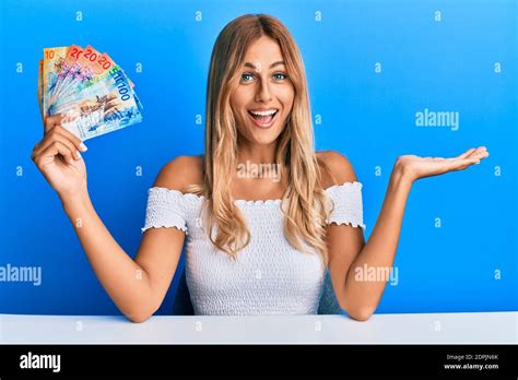 Schöne blonde junge Frau hält schweizer Franken Banknoten feiern Leistung Mit glücklichen
