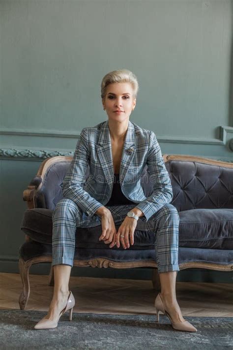 Successful Pretty Blonde Short Haired Woman In Blue Suit Sitting On The Blue Sofa Stock Photo