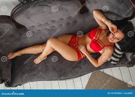 Curvy Tanned Woman In Red Lingerie With Decorative Straps On Sofa Stock Photo Image Of Girl