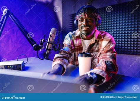 African Radio Host Sitting At Desk Recording In Studio With Microphone