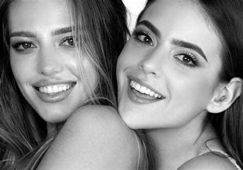 Zwei lächelnde attraktive Freundinnen blonde und brünette auf weißem Hintergrund Nahaufnahme