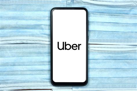 Uber company logo on smartphone screen over the face masks. Global ...