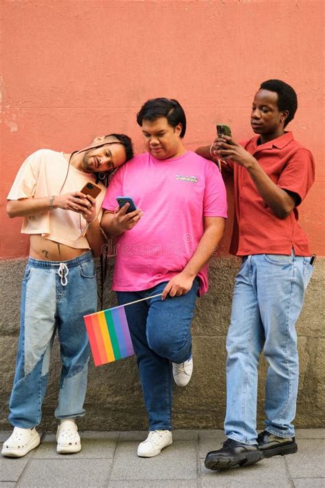 Three Gay Men Are Standing Next To Each Other All Looking At Their Cell Phones Stock Photo