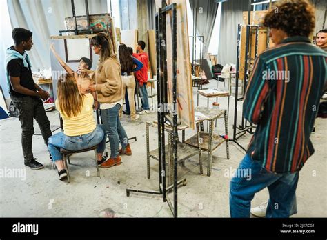 Professeur mature travaillant avec des élèves de l art pendant la classe de peinture à l école