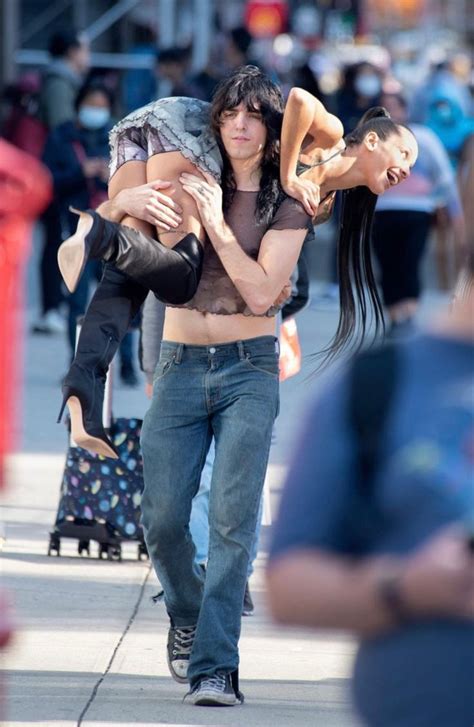 A Man Carrying A Woman On His Back While Walking Down The Street With