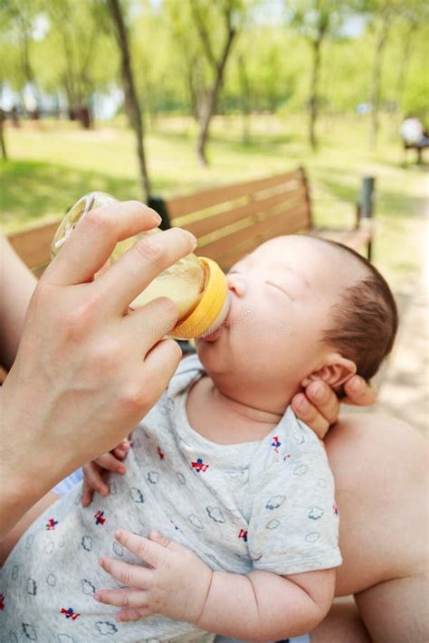 A Portrait Of Korean Newborn Baby Boy Being Fed By Her Father Using