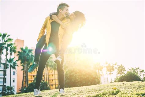 Happy Lesbian Couple Piggyback Having Fun And Laughing While Looking Each Other Eye In A Park