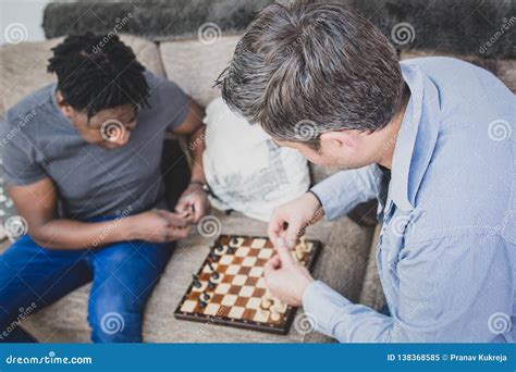 A Gay Couple Enjoying Time Indoors At Home Playing Chess Stock Image