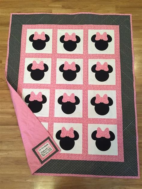 A Pink And Black Quilt With Minnie Mouse Heads On It Sitting On Top Of