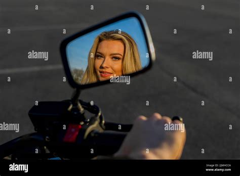 A Lovely Blonde Model Enjoys The Outdoor Weather While Posing With Her Motorcycle Stock Photo