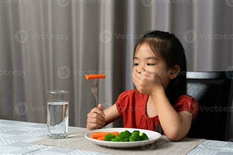 Little cute kid girl refusing to eat healthy vegetables. Children do
