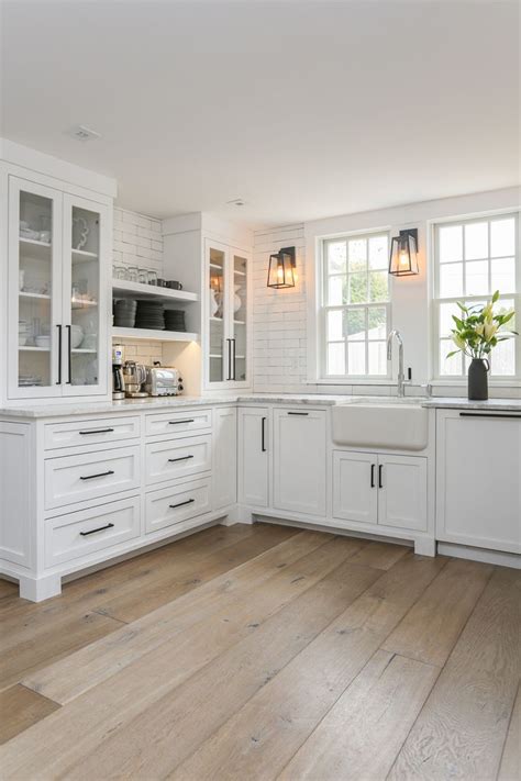 A Kitchen With White Cabinets And Wood Floors