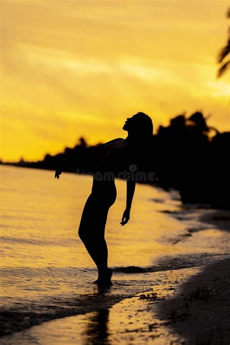 A Nude Latin Model Poses Against The Colorful Sky As The Sun Rises On The Pacific Ocean In Baja