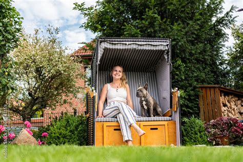 Junge Blonde Frau Sitzt Mit Ihrem Hund Im Eigenen Strandkorb Im Garten Stock Photo Adobe Stock