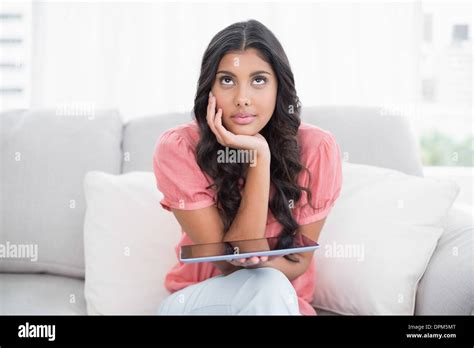 Thoughtful Cute Brunette Sitting On Couch Holding Tablet Stock Photo Alamy