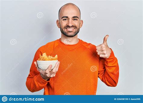 Young Bald Man Holding Nachos Potato Chips Smiling Happy And Positive