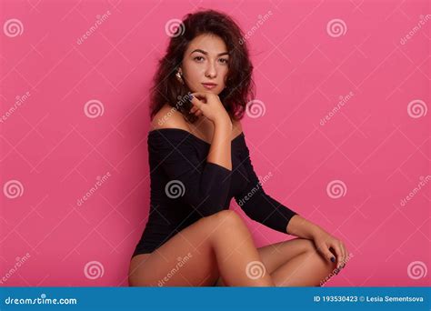 Brunette Woman Sitting On A Floor Sensual Female Model Wearing Black Body Keeping Hand Under