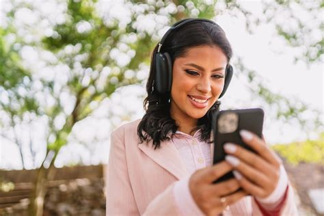 Hermosa chica latina usando su teléfono móvil en el parque Foto Premium