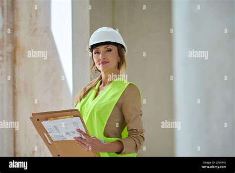 Pretty Female Realtor In Hardhat Takes Notes In Her Folder Stock Photo