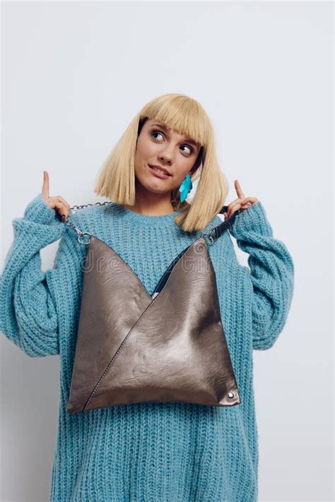 A Beautiful Modest Attractive Blonde Stands On A Light Background In A Stylish Blue Sweater