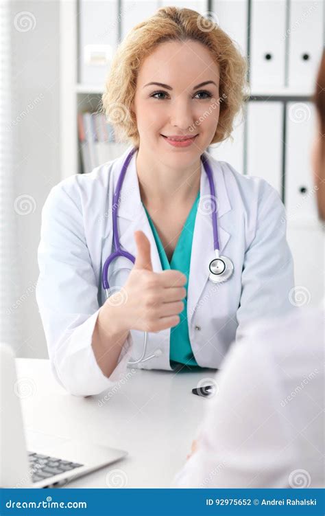 Happy Blonde Female Doctor Looking At Patient While Speaking To Her And Thumbs Up Medicine