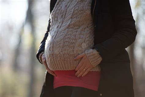 Pregnant Woman Touching Her Swollen Belly In Winter Clothes Stock Image