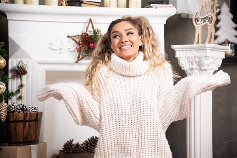 Junge blonde Dame glücklich nahe dem weißen Kamin sitzt Kostenlose Foto