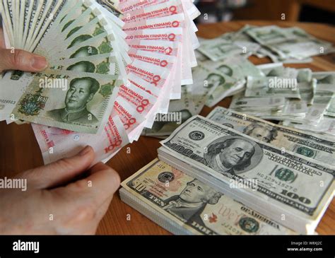 --FILE--A Chinese resident counts his RMB (renminbi) yuan and US dollar