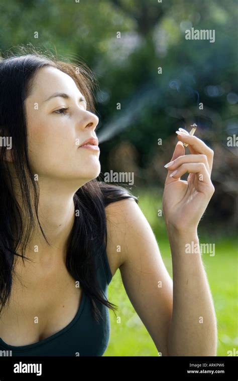 Woman Smoking A Roll Up Cigarette Outside In Garden Stock Photo