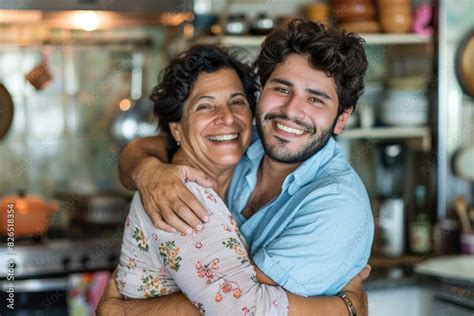 Cheerful Man Embracing His Mature Mother In The Kitchen Bonding Moment Between Son And Mother
