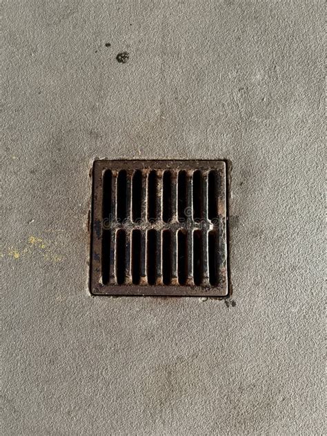 A Close Up View Of A Rusted Metal Drain Grate Embedded In A Concrete